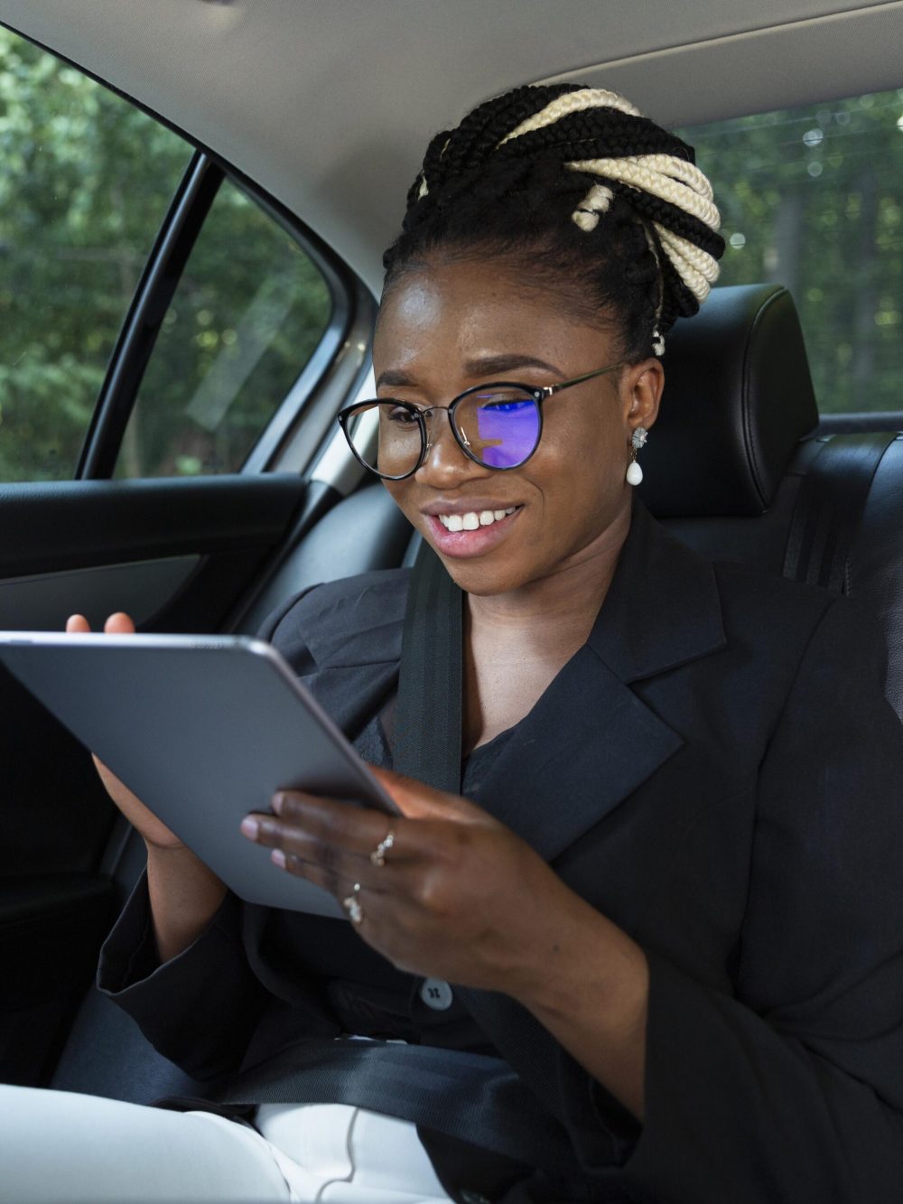 smiley-woman-back-seat-her-car-looking-tablet
